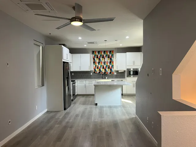 a kitchen with stainless steel appliances a sink a stove a refrigerator cabinets and a kitchen island