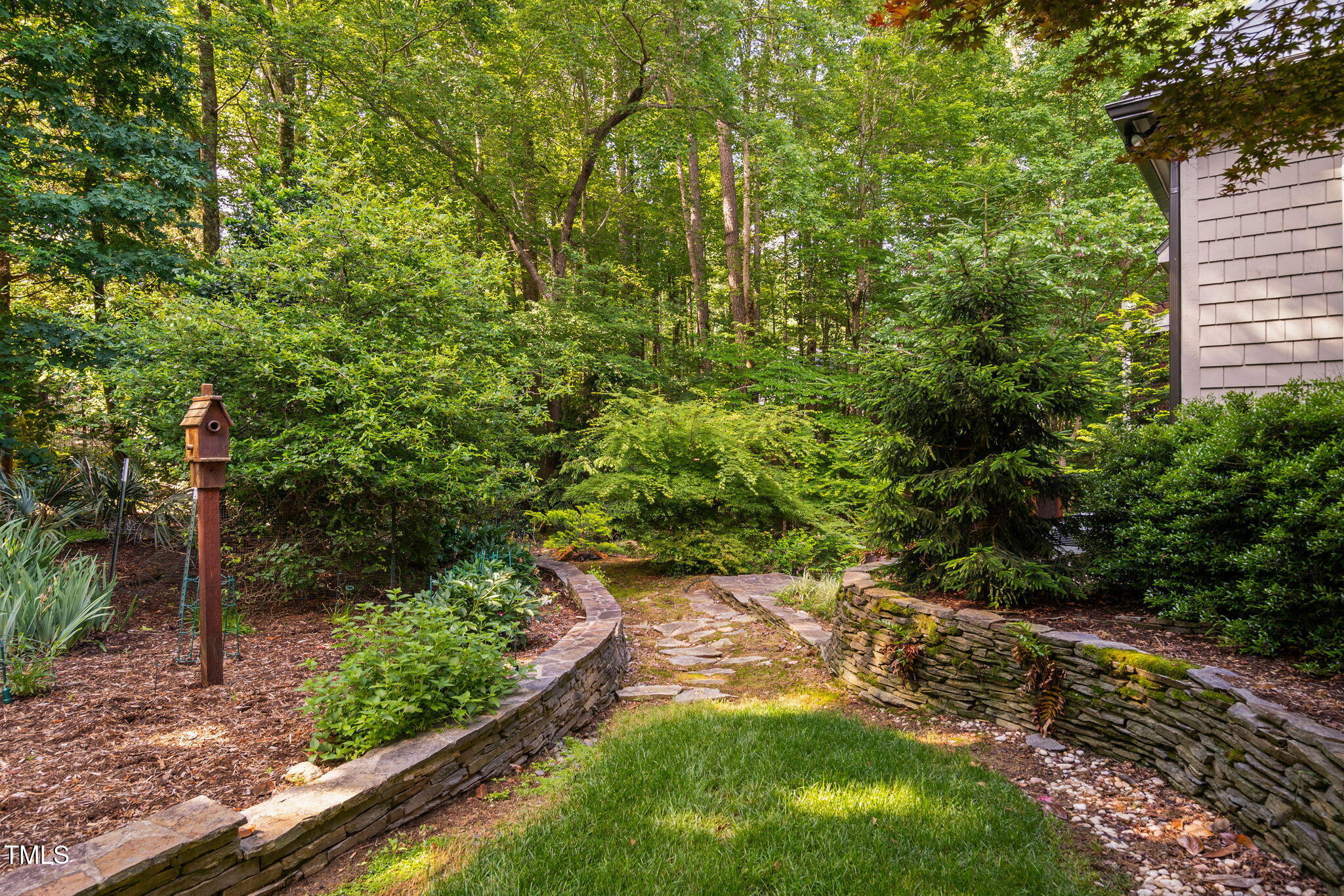10405 Veasey Mill Road Raleigh, NC 27615 - Photo 66 of 94 a view of a yard with plants and a bench