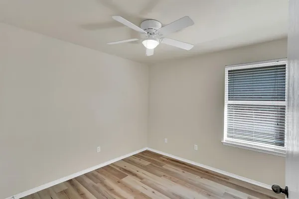 an empty room with a window and a fan