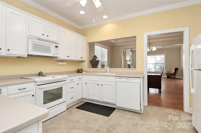 a kitchen with granite countertop white cabinets and white appliances