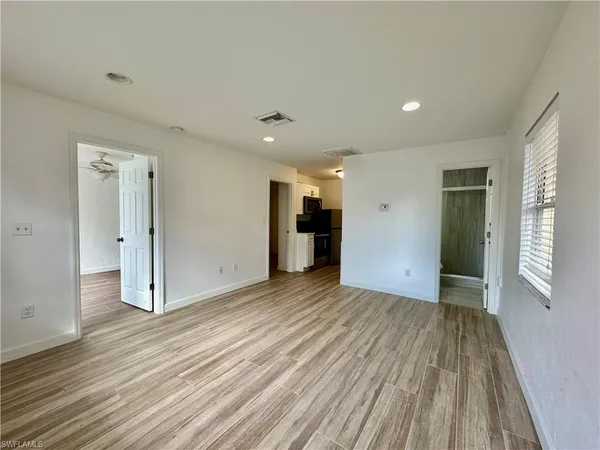 an empty room with wooden floor and windows