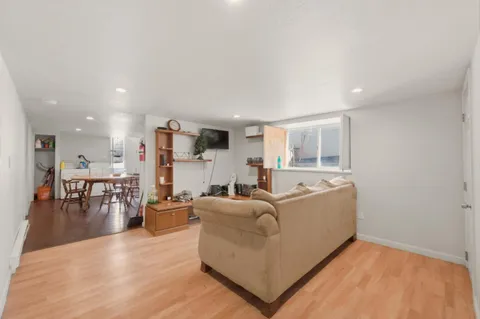 a living room with furniture and kitchen view with wooden floor