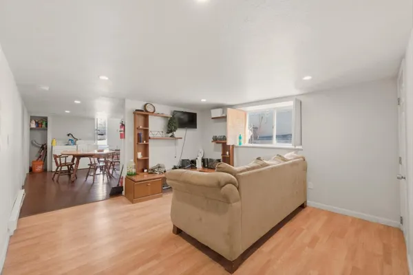 a living room with furniture and kitchen view with wooden floor