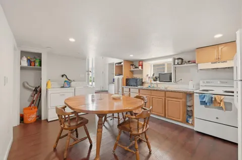 a kitchen with stainless steel appliances kitchen island granite countertop a dining table chairs and white cabinets