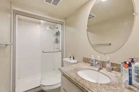 a bathroom with a granite countertop sink toilet and shower