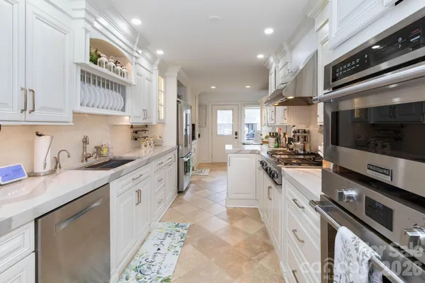 a large kitchen with stainless steel appliances granite countertop a large stove top oven a sink dishwasher and cabinets with wooden floor