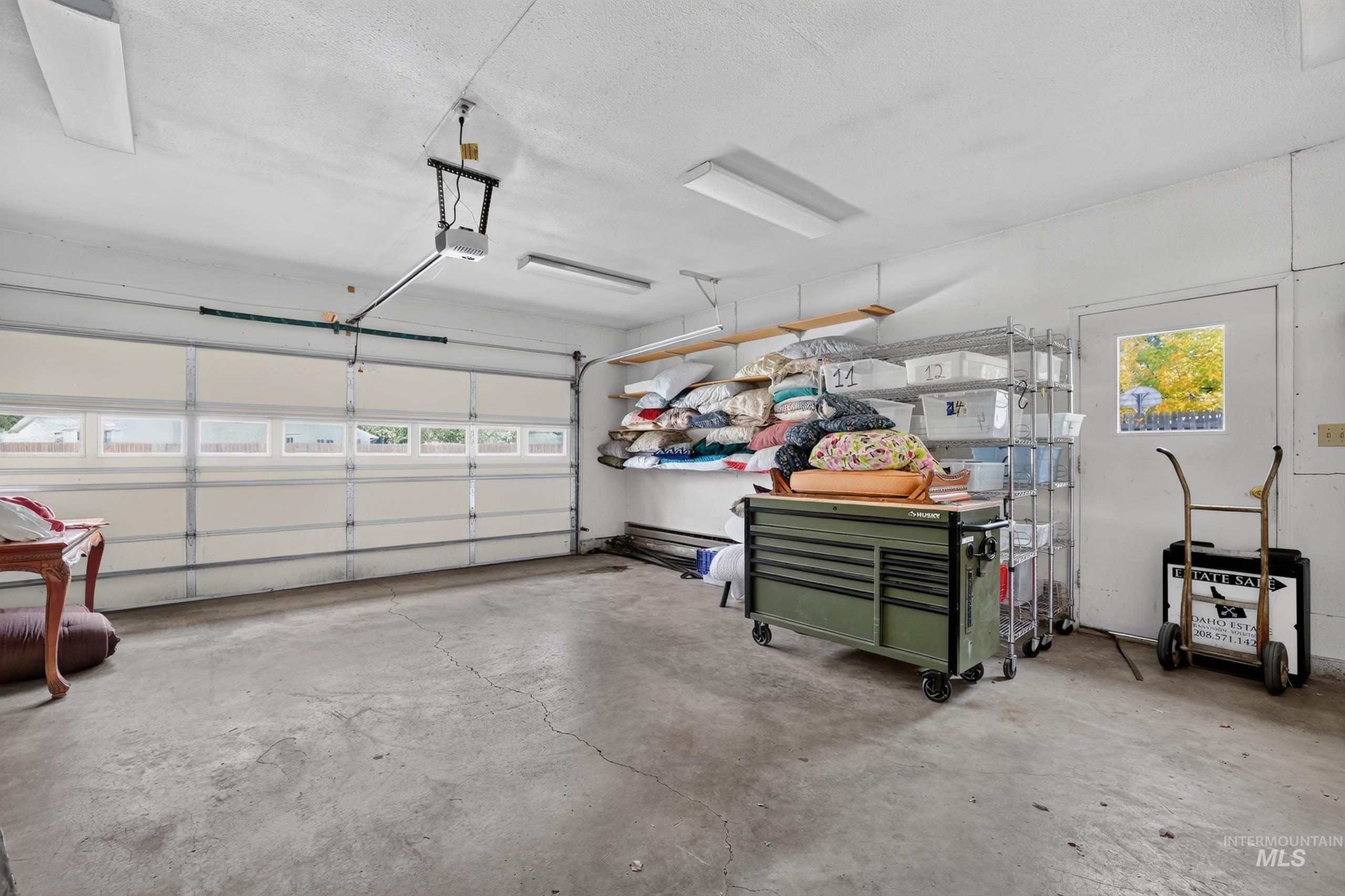 9055 West Highlander Road Boise, ID 83709 - Photo 37 of 39 Attached garage with a sectional overhead door, concrete flooring, overhead fluorescent lighting, and a side access door