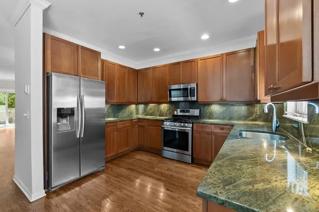 a kitchen with granite countertop a refrigerator and a stove top oven