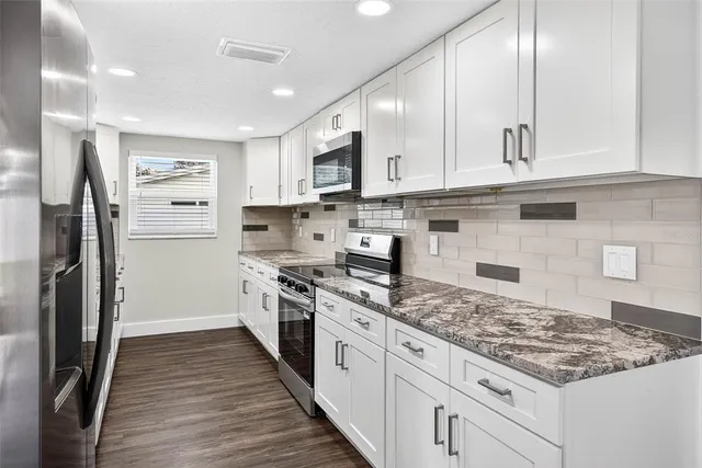 a kitchen with stainless steel appliances granite countertop a stove refrigerator and cabinets