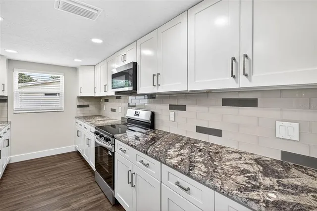 a kitchen with stainless steel appliances granite countertop a stove a sink and a refrigerator