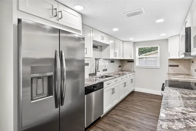a large kitchen with stainless steel appliances granite countertop a refrigerator and a stove top oven