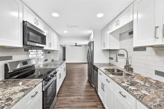 a large kitchen with stainless steel appliances granite countertop a lot of counter space a sink and a stove
