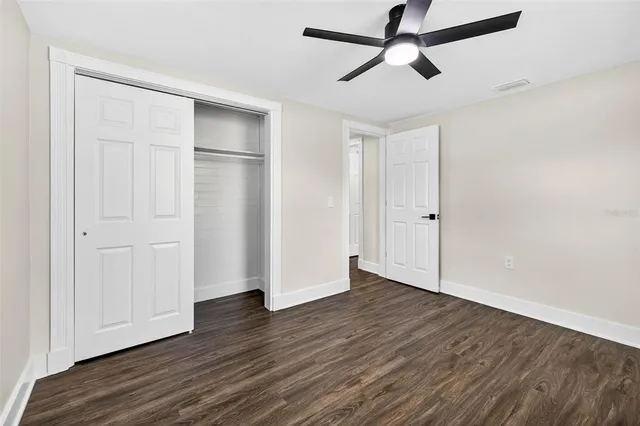 a view of empty room with wooden floor and ceiling fan
