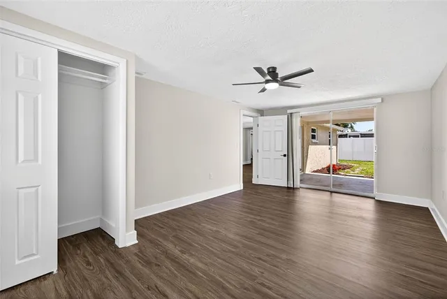 an empty room with wooden floor and a ceiling fan