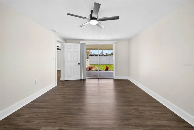 a view of an empty room with window and wooden floor