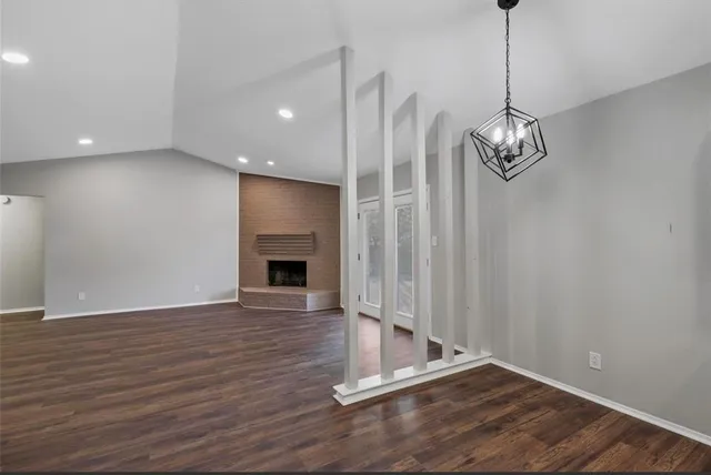 a view of a livingroom with wooden floor staircase and a kitchen space