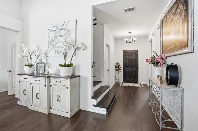 a hallway with white cabinets and chandelier