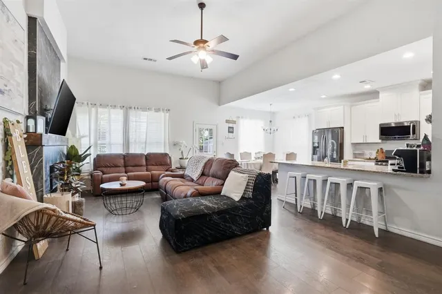 a living room with furniture kitchen view and a wooden floor