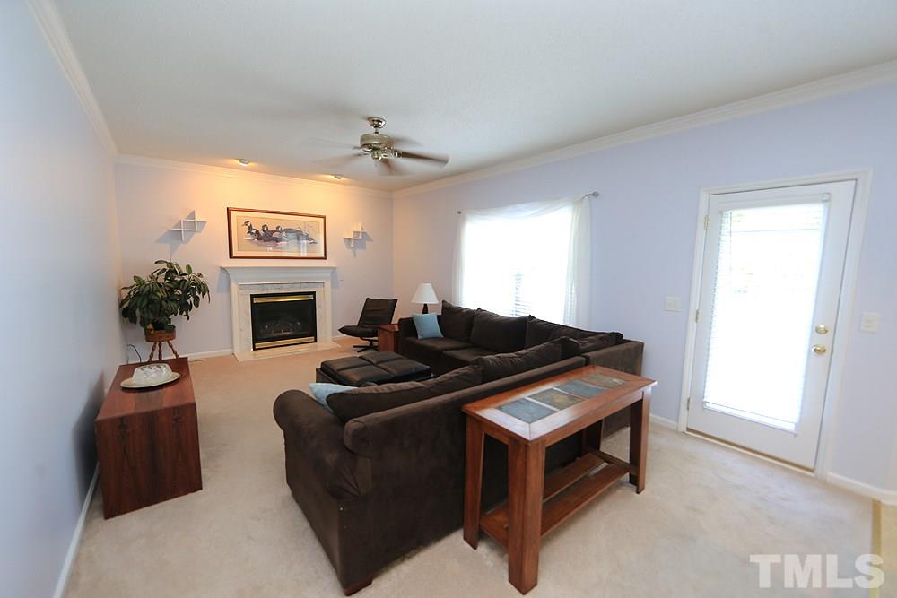 8313 Trumpetor Way Raleigh, NC 27613 - Photo 6 of 21 a living room with furniture a fireplace and a flat screen tv