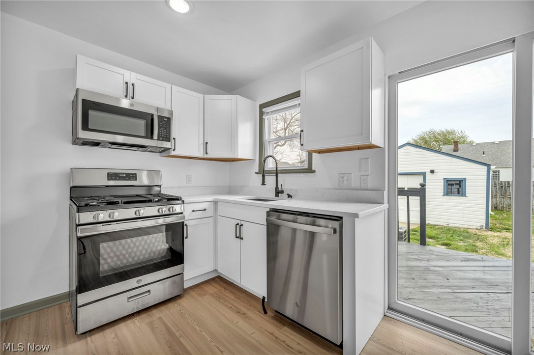 1609 Mapledale Road Wickliffe, OH 44092 - Photo 14 of 46 Kitchen with sink, stainless steel appliances, light hardwood / wood-style floors, and white cabinetry
