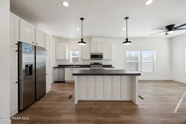 a kitchen with stainless steel appliances granite countertop a refrigerator a sink a stove and a wooden floors