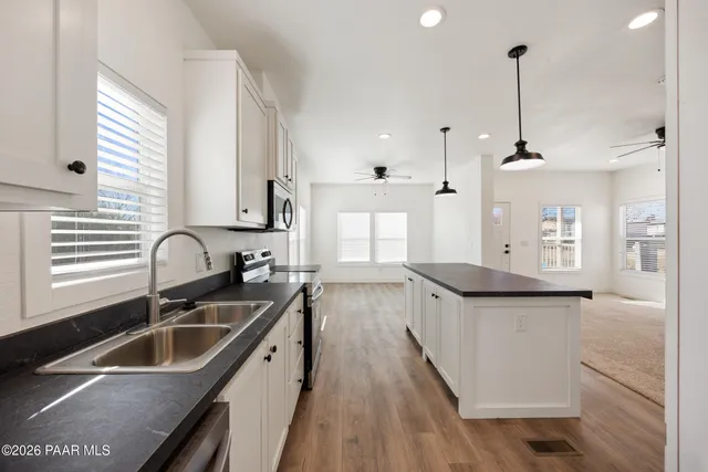 a kitchen with stainless steel appliances granite countertop a sink a stove and a wooden floors
