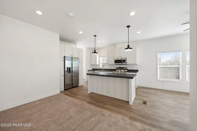 a kitchen with stainless steel appliances kitchen island granite countertop a refrigerator a sink a stove and a wooden floors