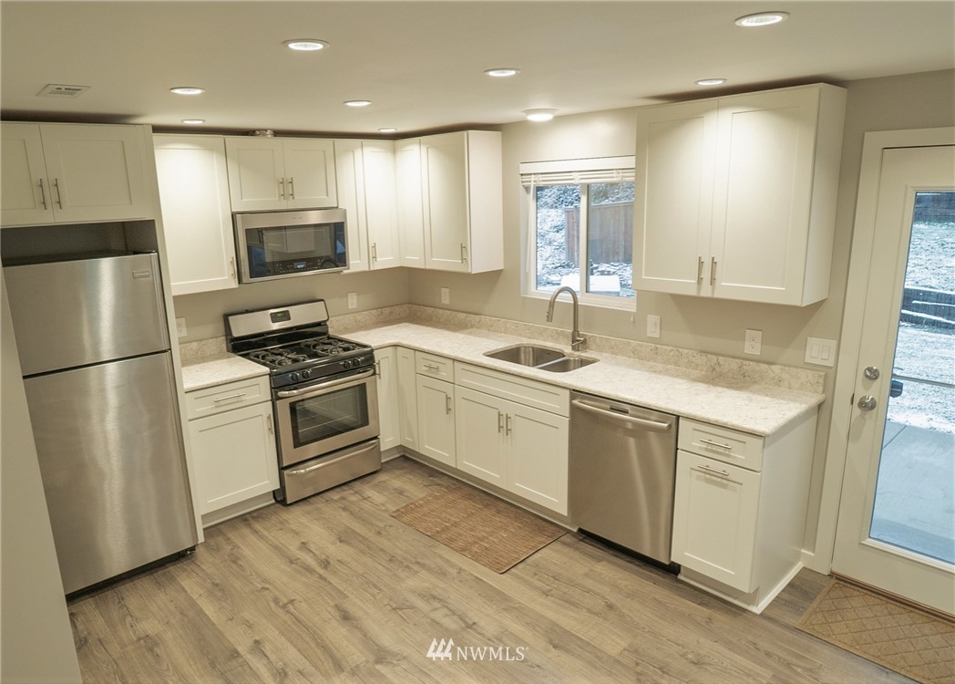 3436 Southeast 5th Street Renton, WA 98058 - Photo 7 of 28 a white kitchen with wooden floor and stainless steel appliances