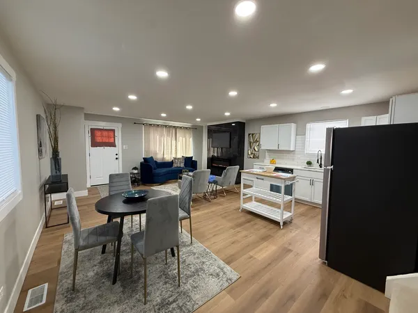 a living room with stainless steel appliances furniture and a wooden floor