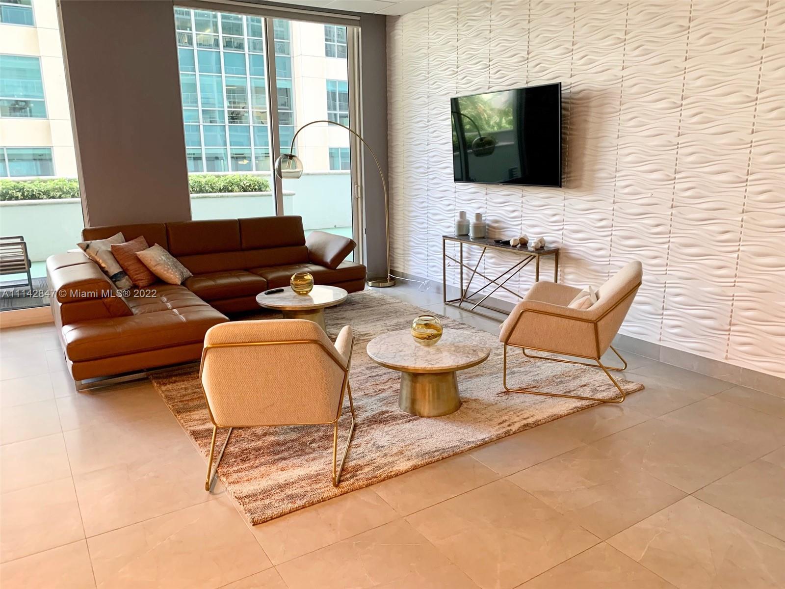 1200 Brickell Bay Drive, Unit 1812 Miami, FL 33131 - Photo 12 of 24 a living room with furniture a flat screen tv and a large window
