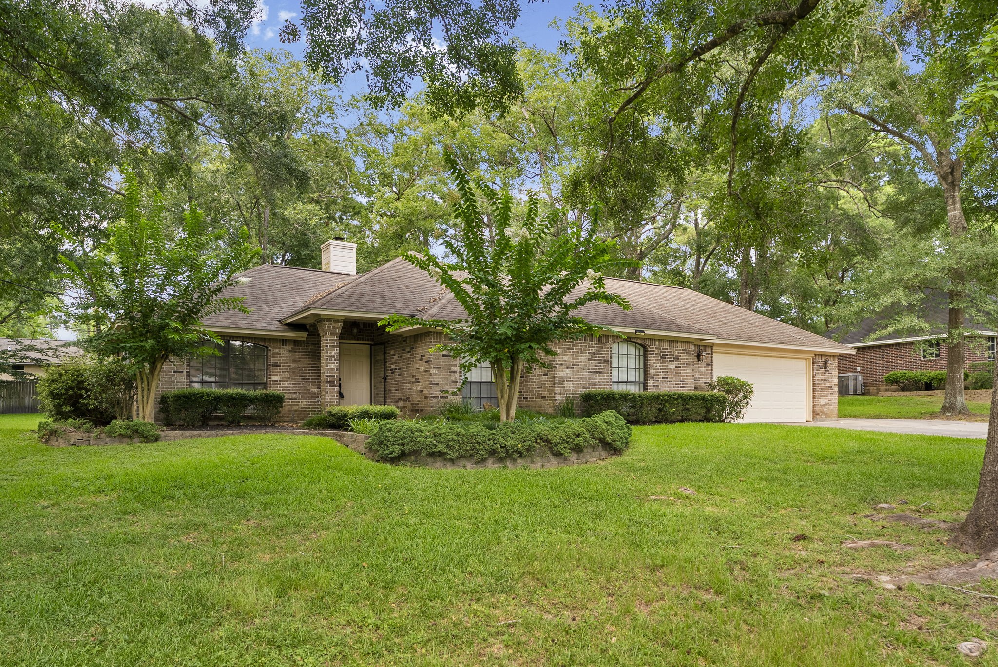 202 Sunset Boulevard Conroe, TX 77303 - Photo 5 of 50 Charming brick home with a cozy front porch, nestled among mature trees. Features a well-maintained lawn, attractive landscaping, and a spacious two-car garage. Peaceful neighborhood setting.