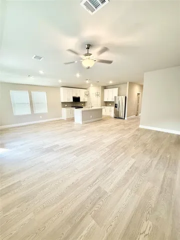 a view of kitchen with stainless steel appliances kitchen island granite countertop a stove a refrigerator a sink dishwasher with a oven and cabinets with wooden floor