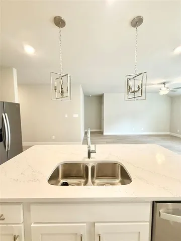 a view of a kitchen with kitchen island a counter top space a sink and cabinets