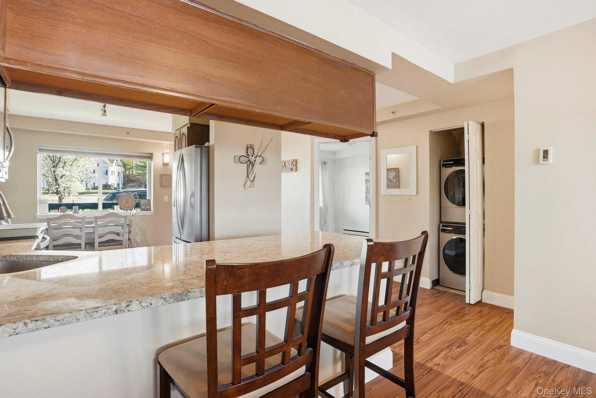 4 Marina Drive, Unit D2 Mahopac, NY 10541 - Photo 13 of 39 The property features a kitchen with granite countertops and stainless steel appliances, a dining area with a window providing outdoor views, and wood flooring throughout