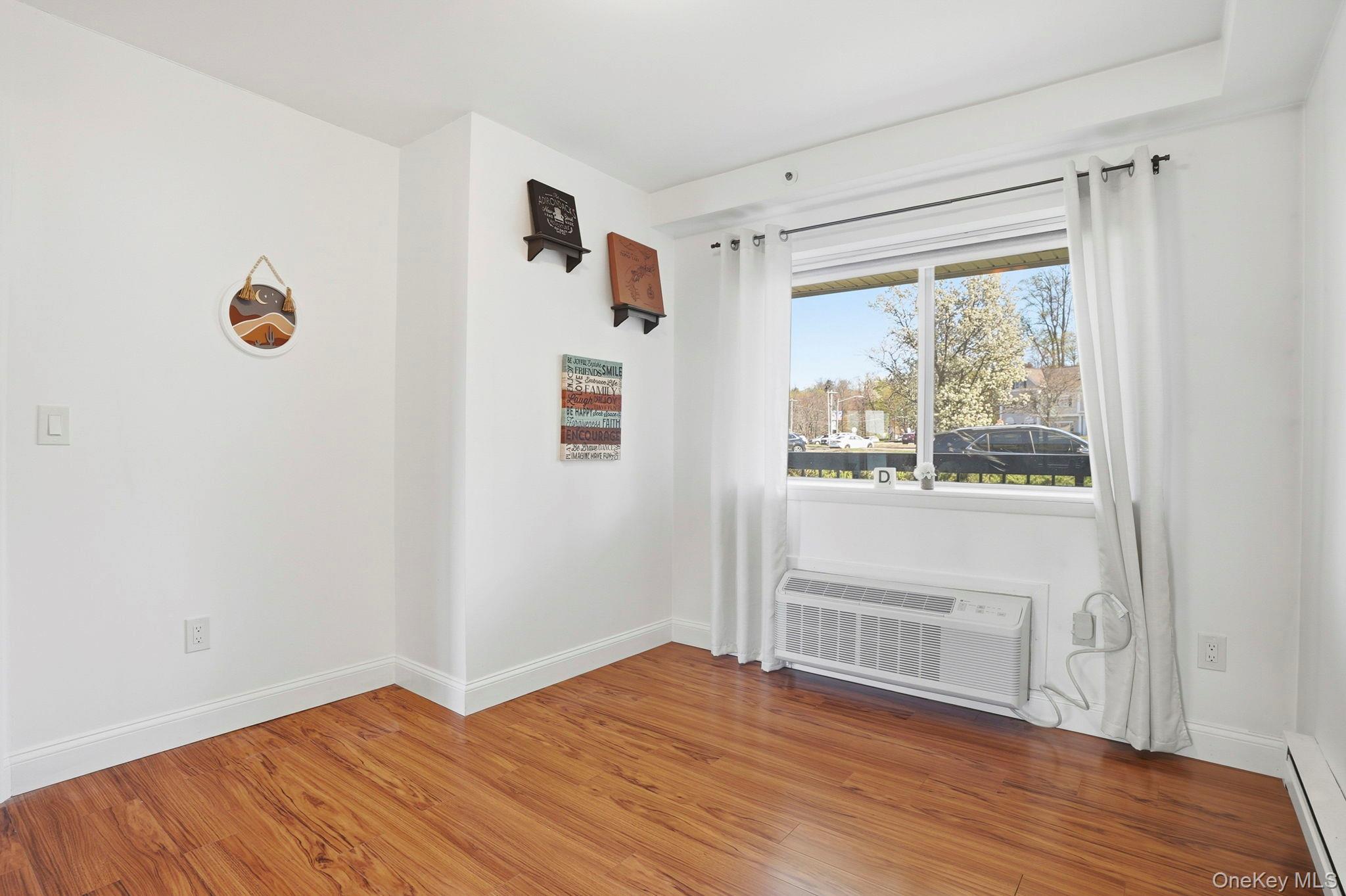4 Marina Drive, Unit D2 Mahopac, NY 10541 - Photo 20 of 39 This living area features a window with white curtains, wood flooring, and white walls
