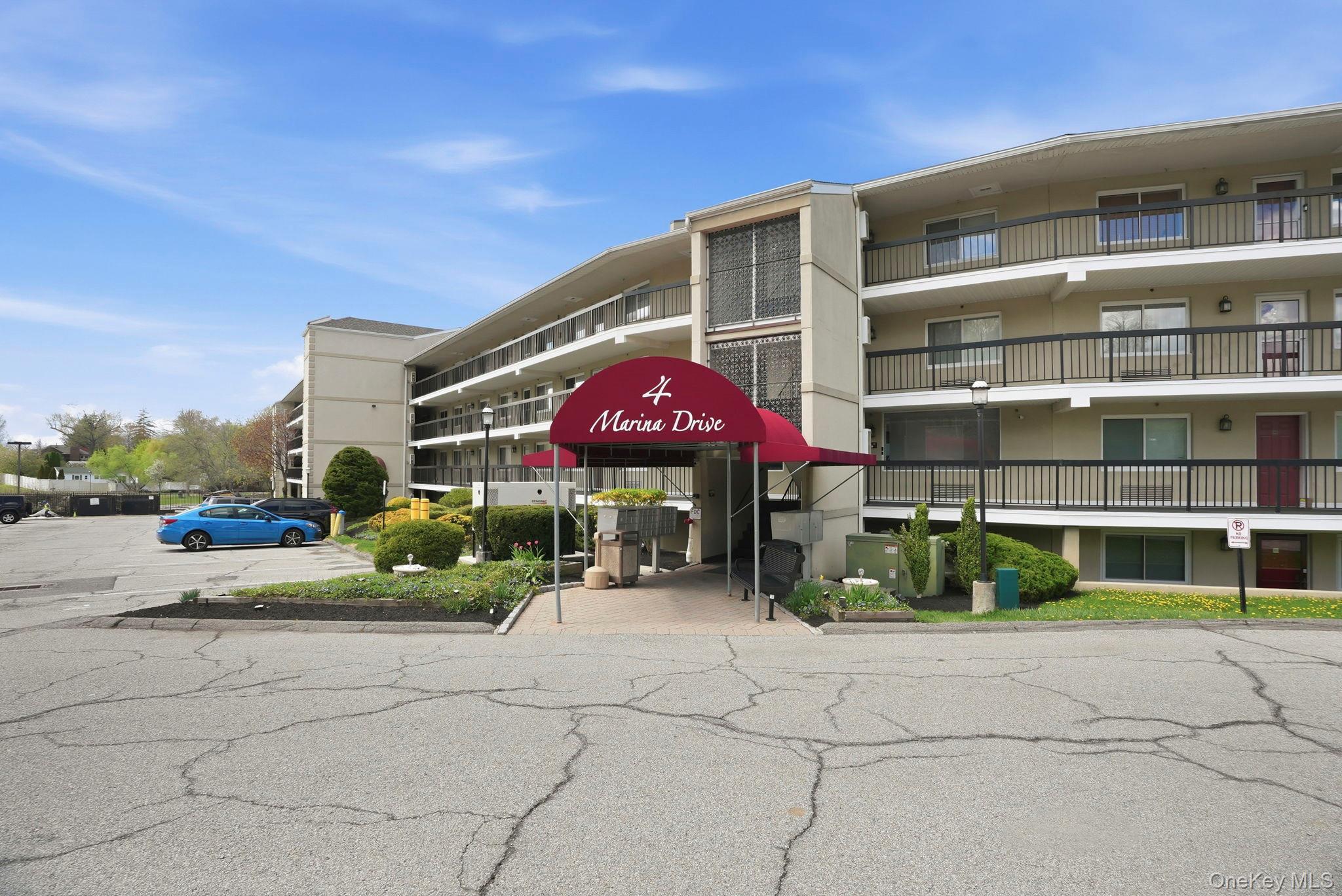 4 Marina Drive, Unit D2 Mahopac, NY 10541 - Photo 2 of 39 The property features a multi-story building with balconies, a red awning at the entrance, and a parking area