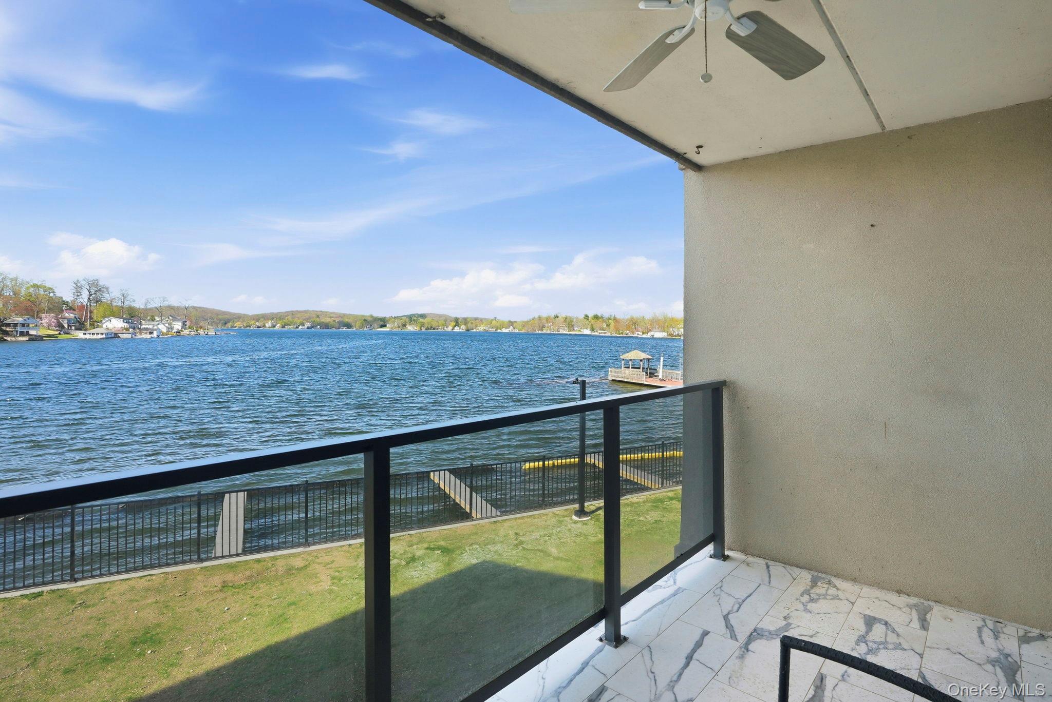 4 Marina Drive, Unit D2 Mahopac, NY 10541 - Photo 25 of 39 Balcony featuring a ceiling fan, tiled flooring, and a glass and metal railing, overlooking a body of water with a dock