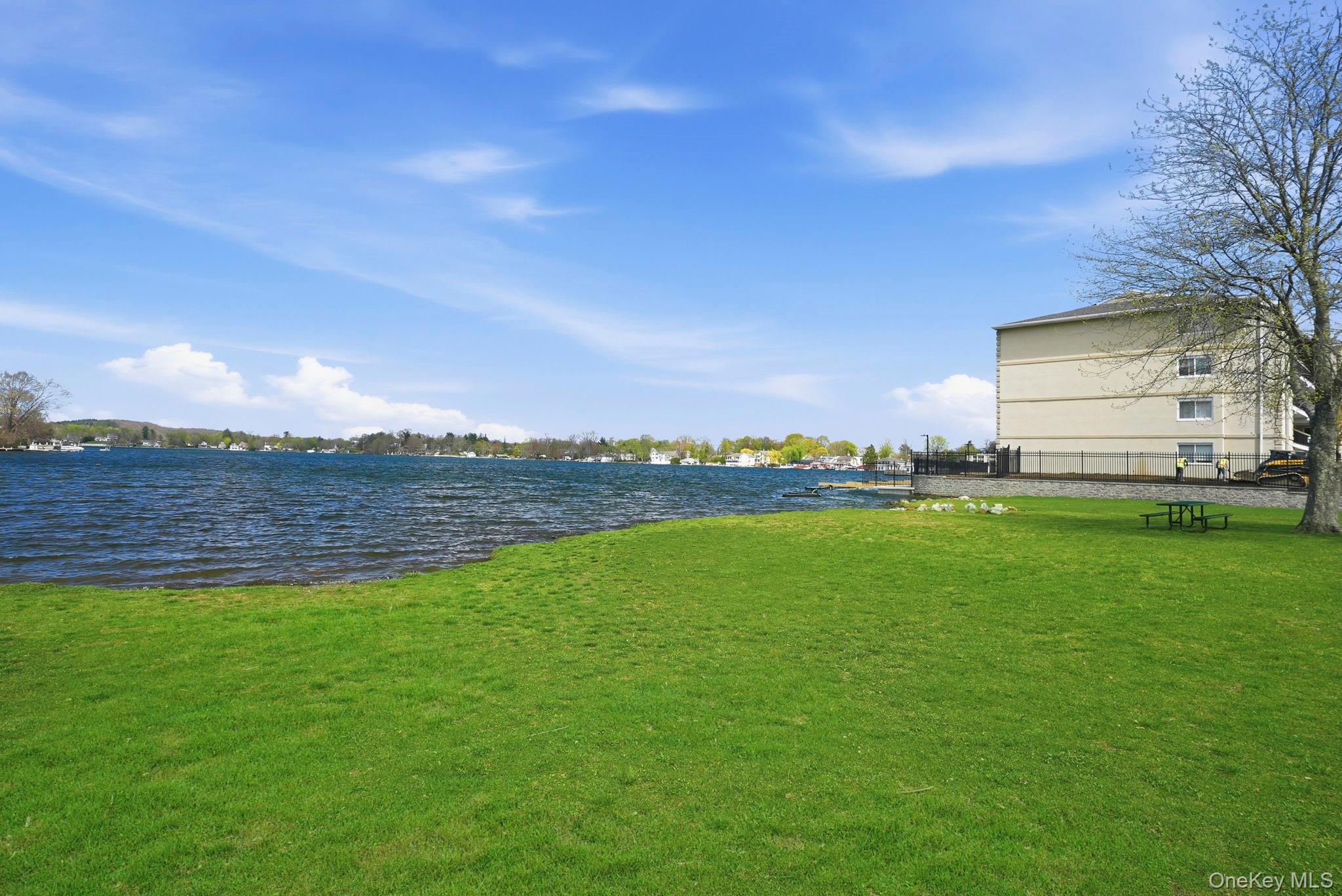 4 Marina Drive, Unit D2 Mahopac, NY 10541 - Photo 27 of 39 Expansive green lawn with water views, featuring a nearby tree and a building with exterior windows