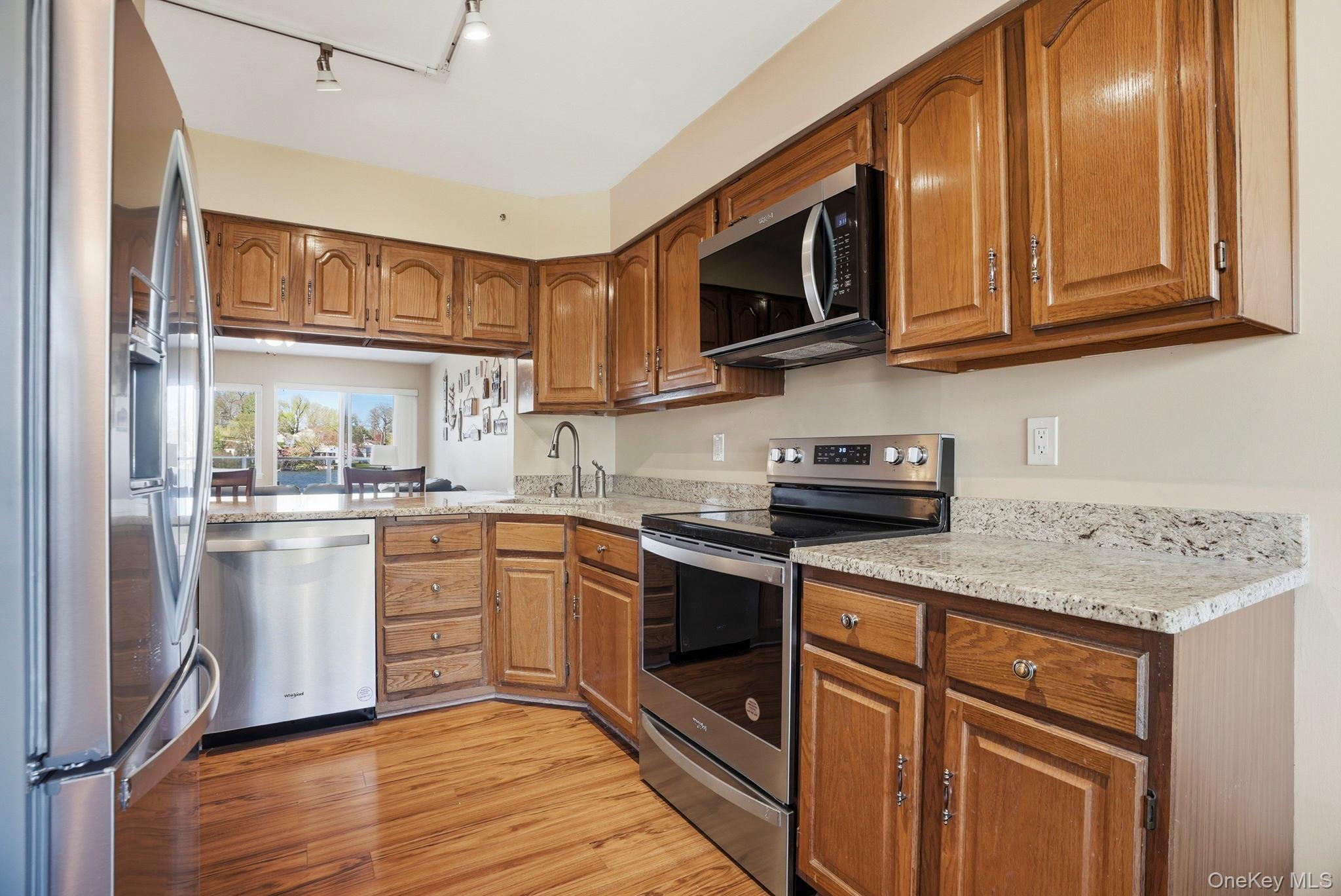 4 Marina Drive, Unit D2 Mahopac, NY 10541 - Photo 9 of 39 The property features a kitchen with wood cabinetry, stainless steel appliances, granite countertops, and hardwood flooring