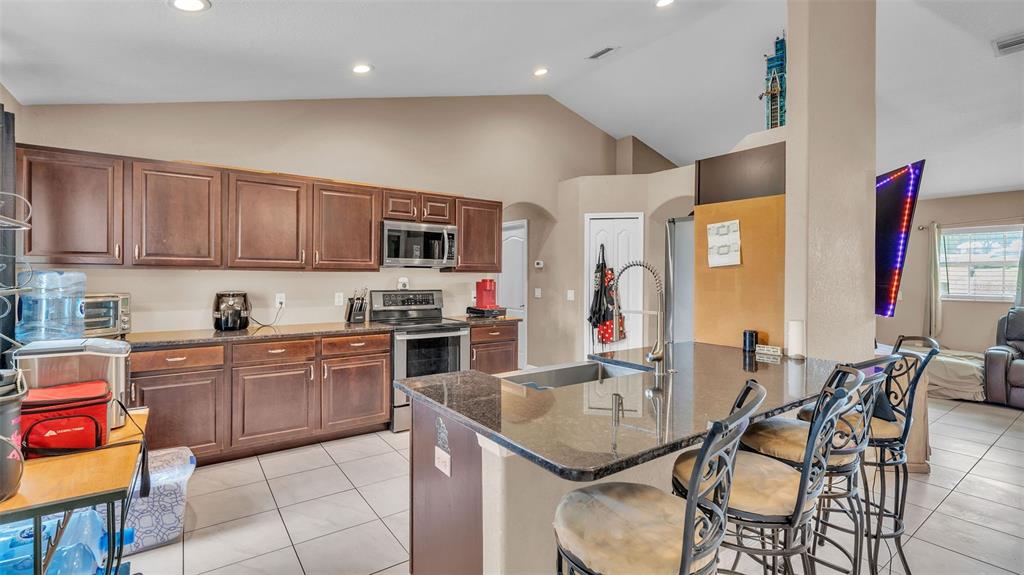 39360 Sparkman Road Dade City, FL 33525 - Photo 10 of 40 a kitchen with granite countertop kitchen island stainless steel appliances a stove a sink a dining table and chairs