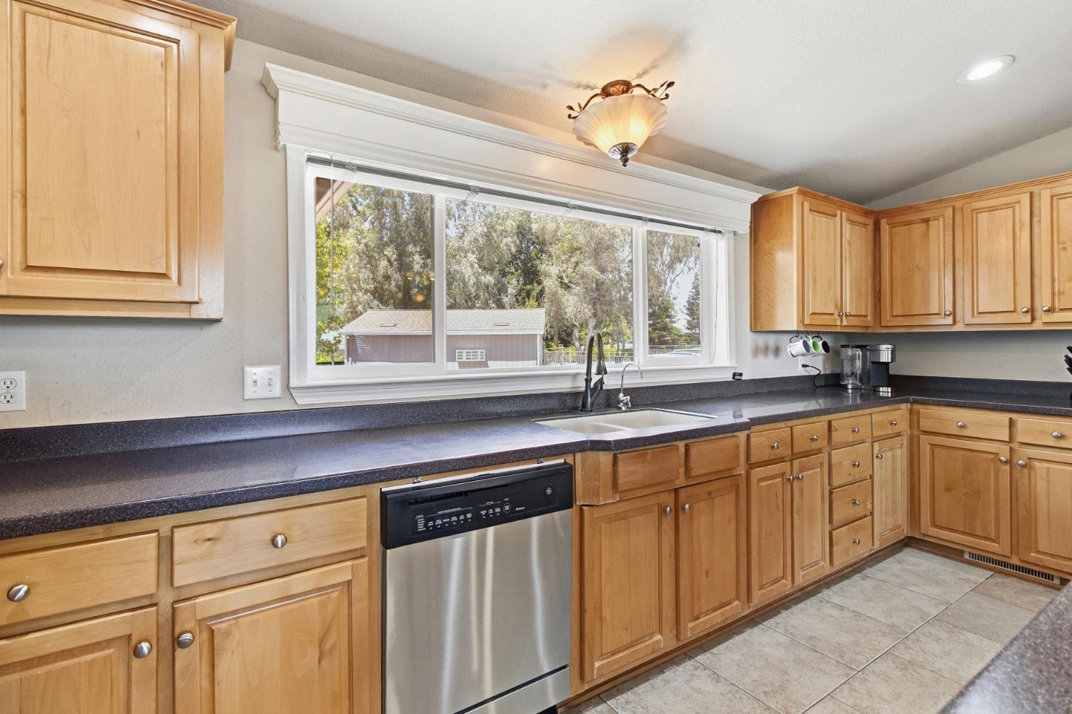 12390 Hobday Road Wilton, CA 95693 - Photo 18 of 92 a kitchen with granite countertop white cabinets a sink and dishwasher with a large window