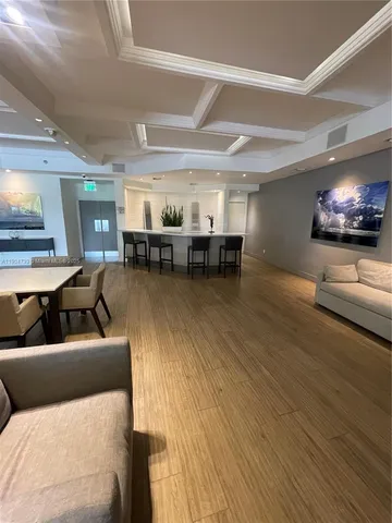a living room with couches and kitchen view with wooden floor