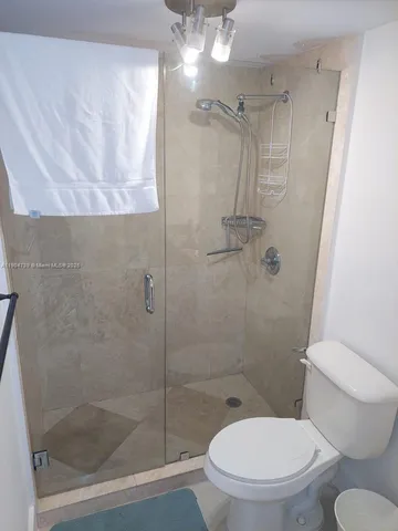 a white toilet sitting next to a shower