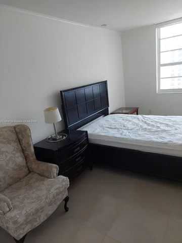 a bedroom with bed couch and window
