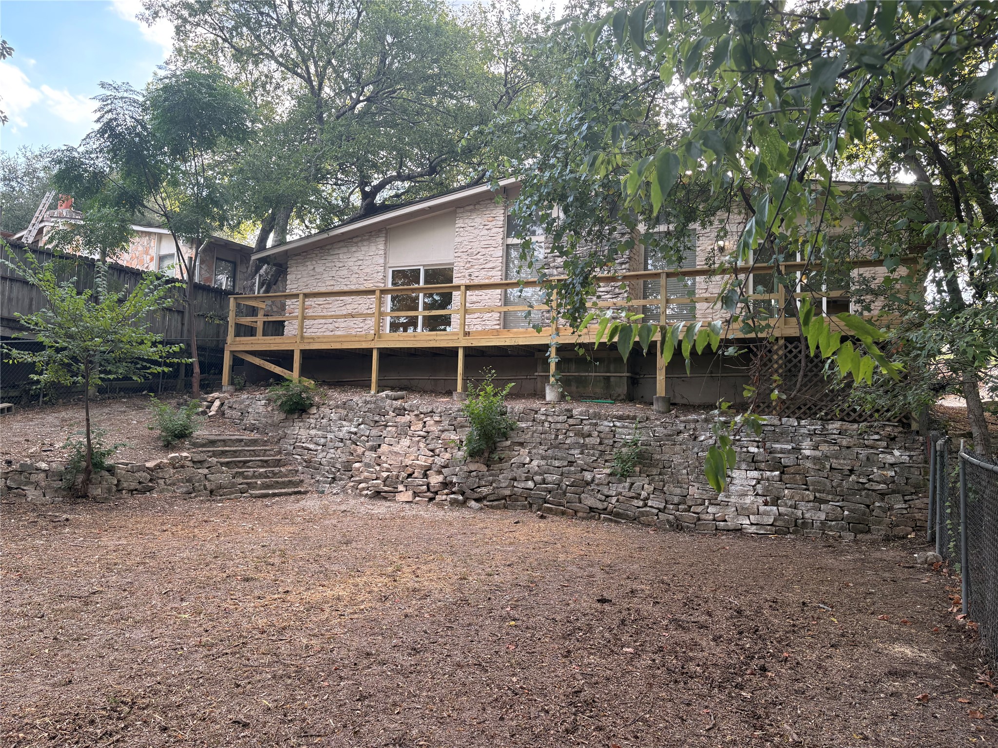 11913 Rennalee Loop Austin, TX 78753 - Photo 36 of 40 A private yard with a natural stone retaining wall supports a home with a spacious deck.