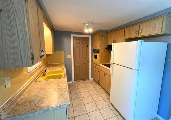 a kitchen with a refrigerator a stove top oven and cabinets