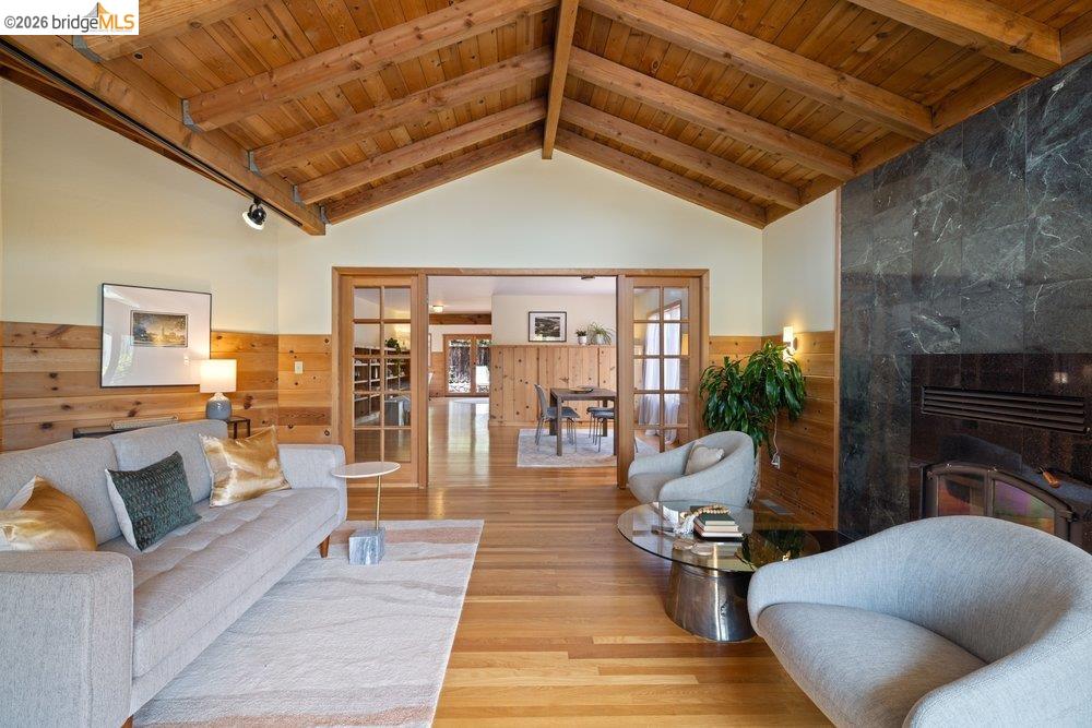 287 Purdue Avenue Kensington, CA 94708 - Photo 13 of 60 Vaulted wood-plank ceiling with exposed beams, hardwood flooring, full-height stone fireplace surround, wood paneling, and glass-paned sliding doors