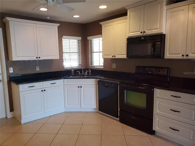 a kitchen with granite countertop white cabinets and black appliances
