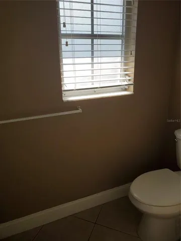 a white toilet sitting in a bathroom next to a window