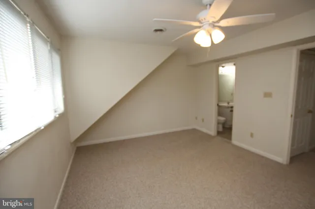 an empty room with windows and fan